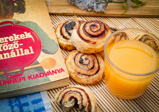 A table topped with pastries next to a glass of orange juice